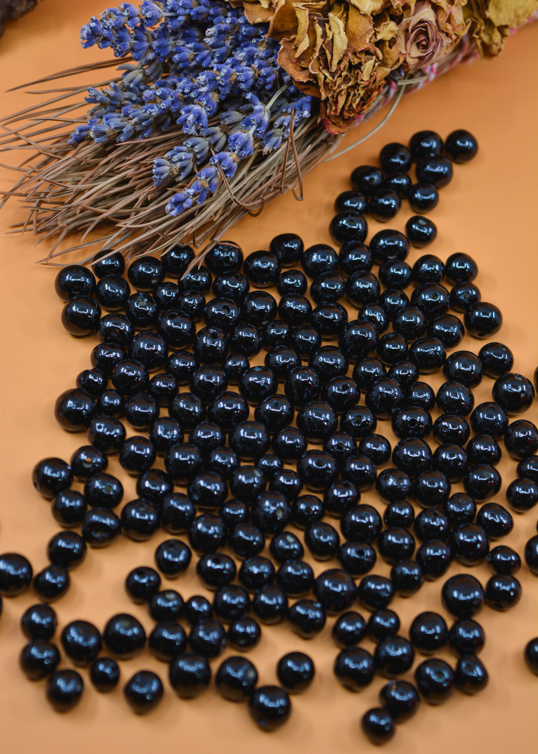 Black Acai Beads displayed in a Orange background.