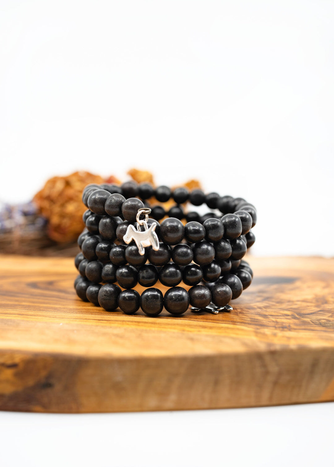 Black acai beads bracelet on a wooden surface, handmade with memory wire.