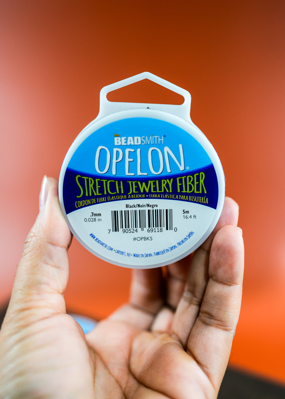 A spool of black stretch jewelry fiber cord labeled 'OPELON Stretch Jewelry Fiber' by BeadSmith, intended for bead bracelets and anklet making.