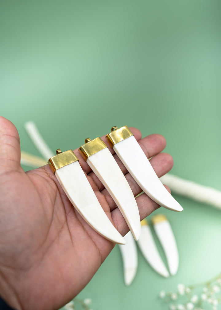 Cream white bone tusk pendant handmade in India from recycled cow bone featuring a polished gold-tone cap. Lightweight tribal-inspired focal pendant perfect for boho jewelry making, macrame necklaces, artisan designs, and statement jewelry.
