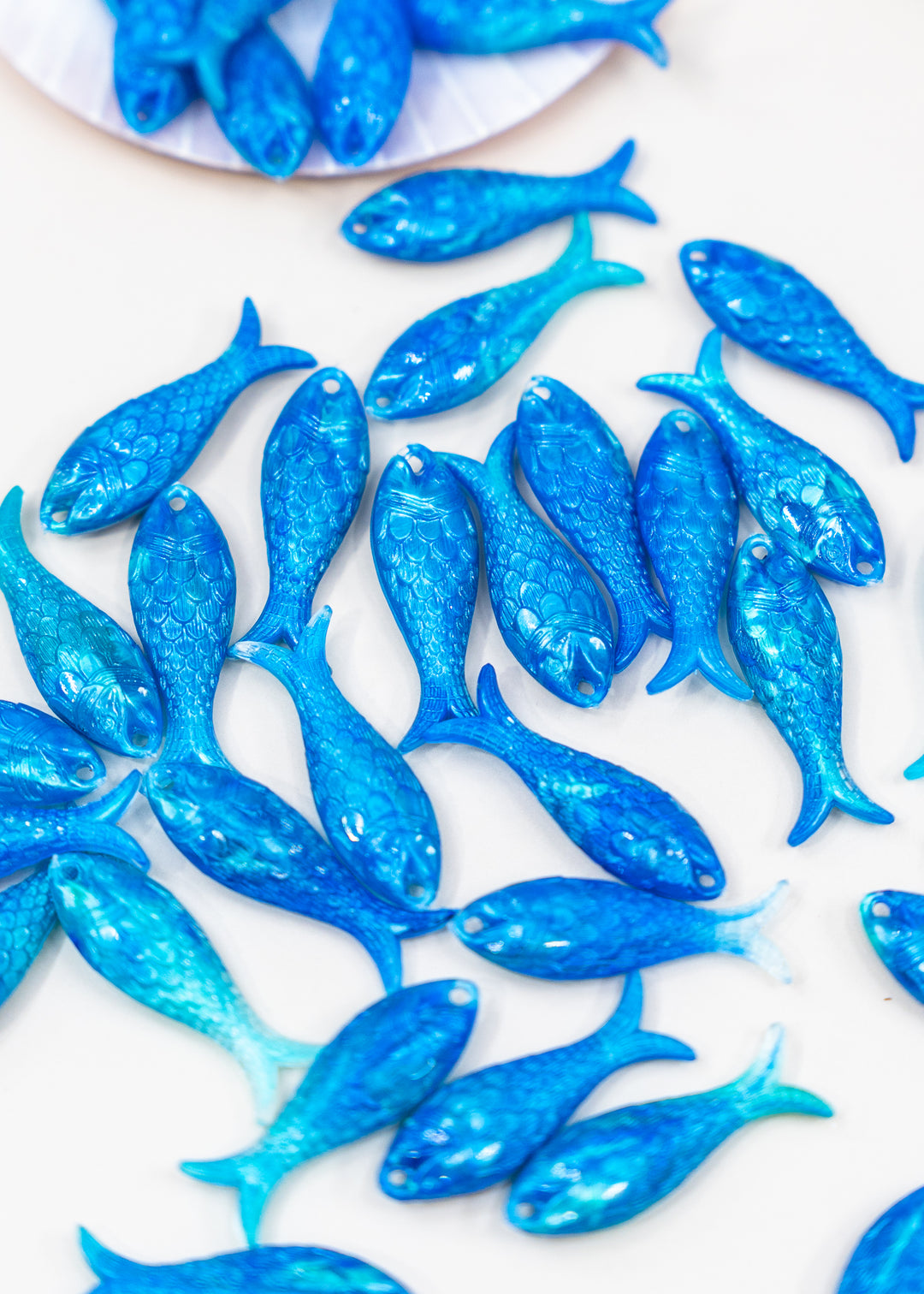 A collection of small, glittery blue fish charms made from German resin for jewelry making.
