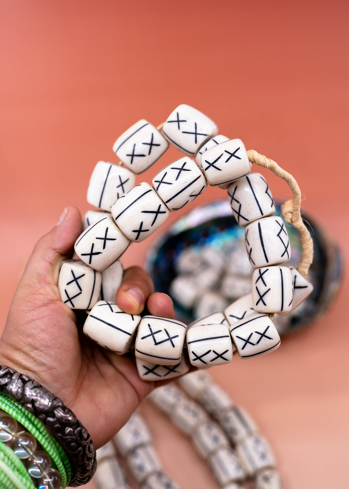 Hand-carved African bone beads handmade in Kenya from recycled cow bone featuring bold tribal X patterns and oversized barrel shapes. Perfect for boho jewelry making, statement necklaces, leather cord projects, macrame, braids, and artisan designs.