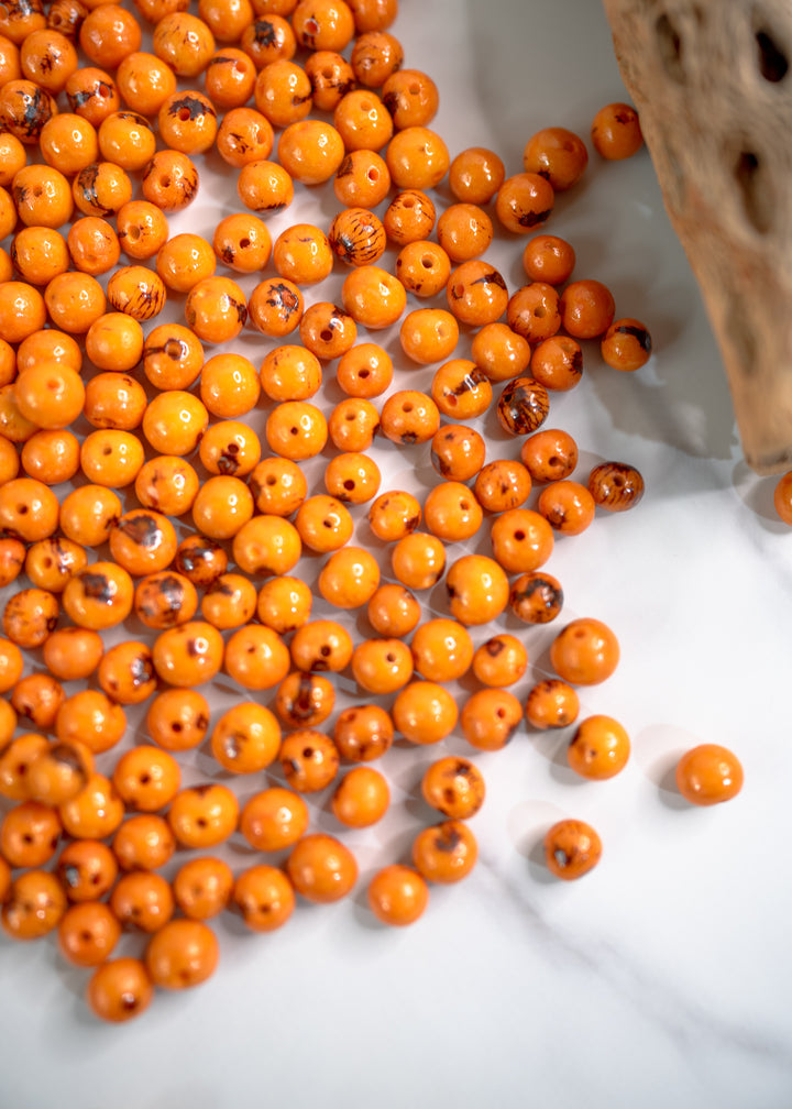 Details of Orange Acai Beads on a white surface.