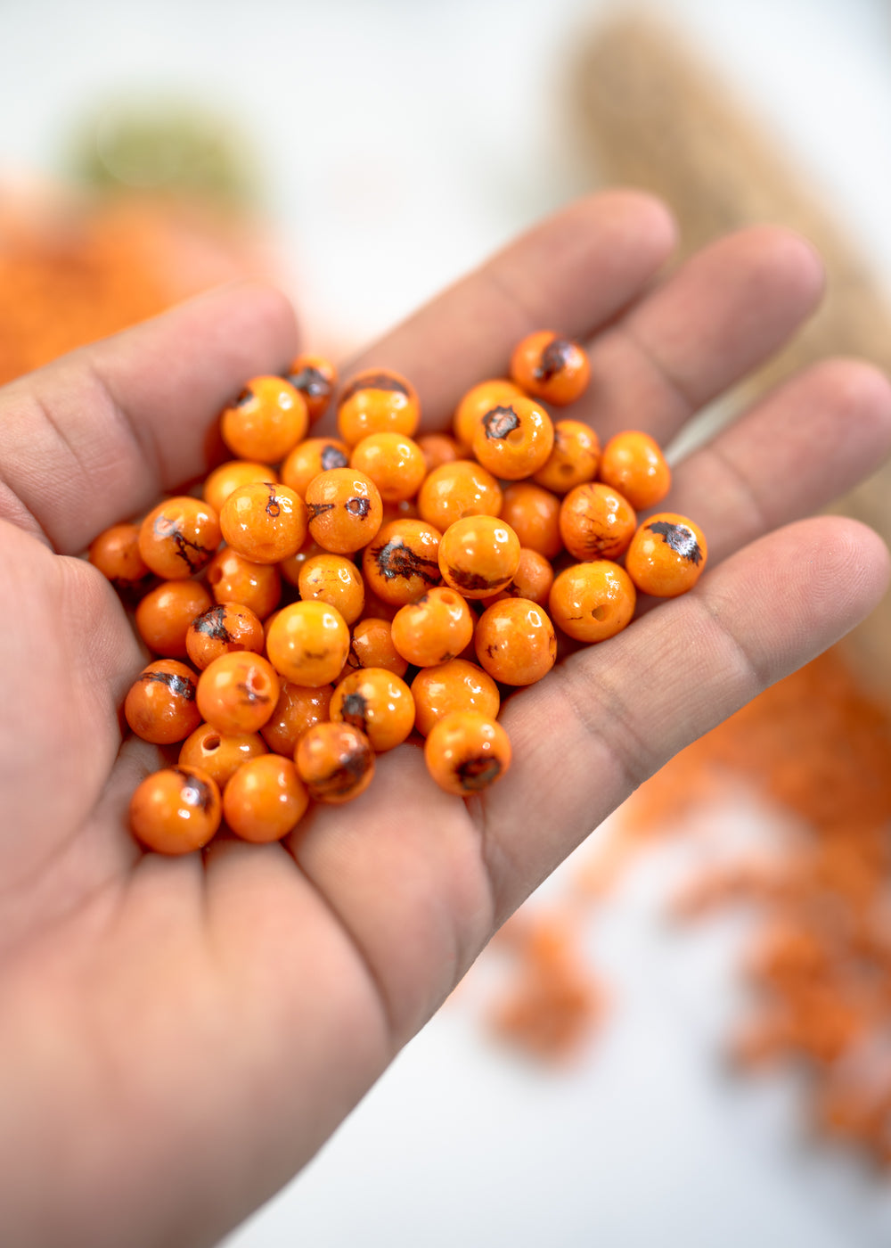 Close-up of Orange acai beads in the hands.