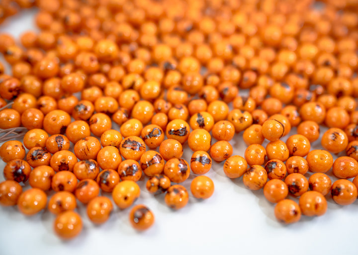 A close-up of natural orange acai beads for DIY jewelry making.