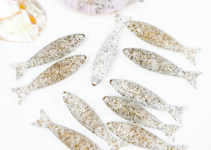 A set of small fish-shaped ornaments or charms with a speckled white and gold pattern fish charms made from German resin for jewelry making.
