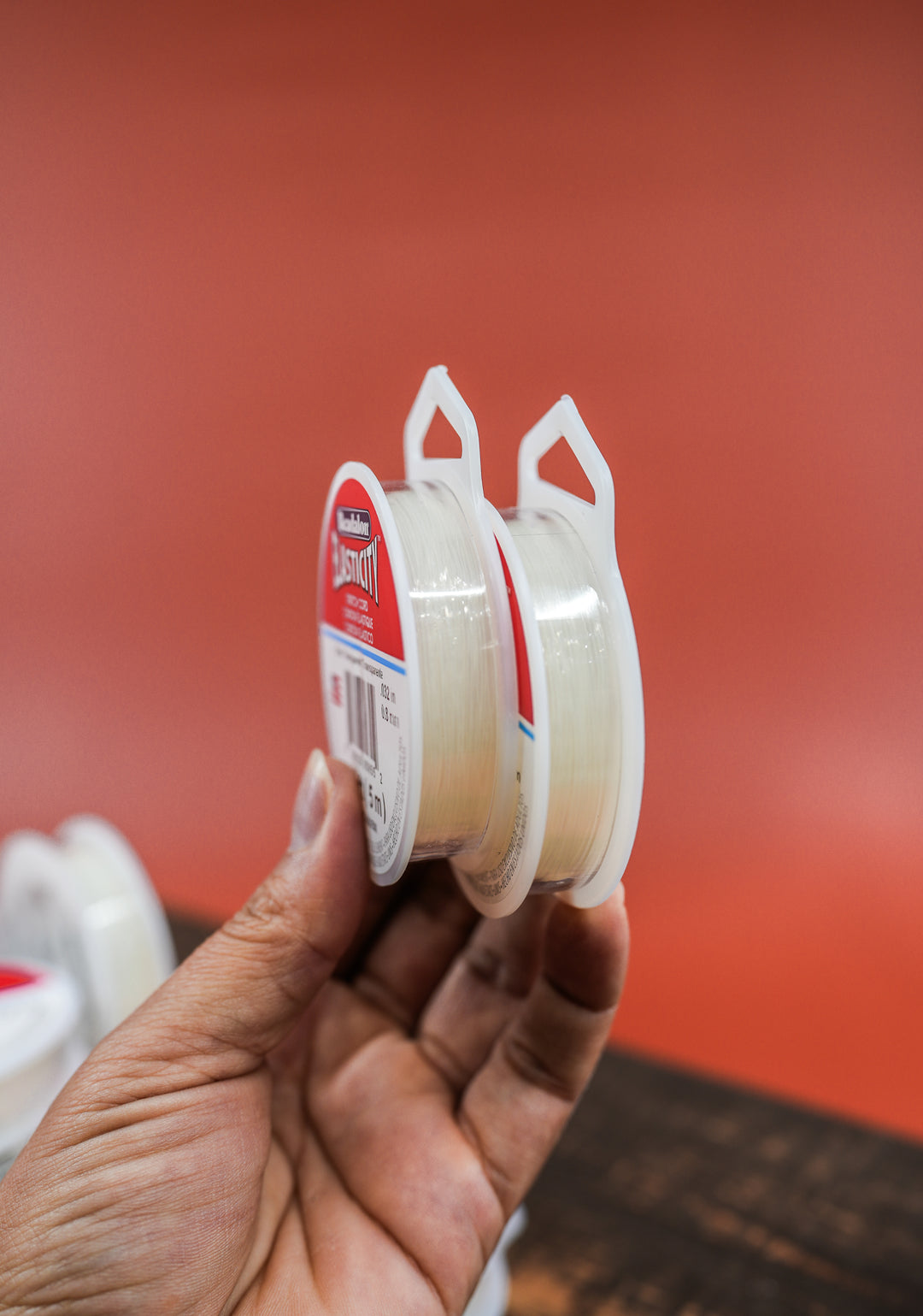 A spool of clear stretch bead elastic cord held in a person&