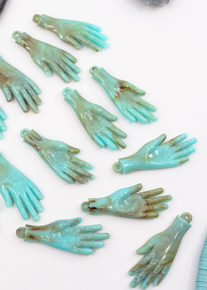 Multiple turquoise and brown German resin hand charms with loop tops, arranged on a plain white background.
