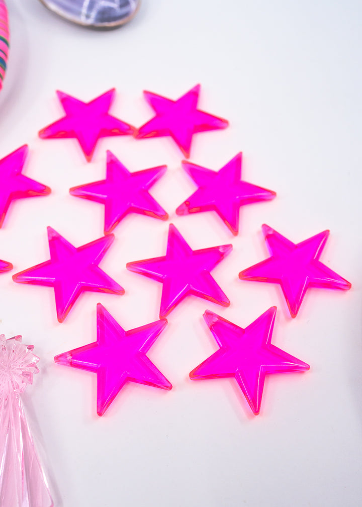 Several bright hot pink translucent star-shaped embellishments charms on a white surface, made from German resin.