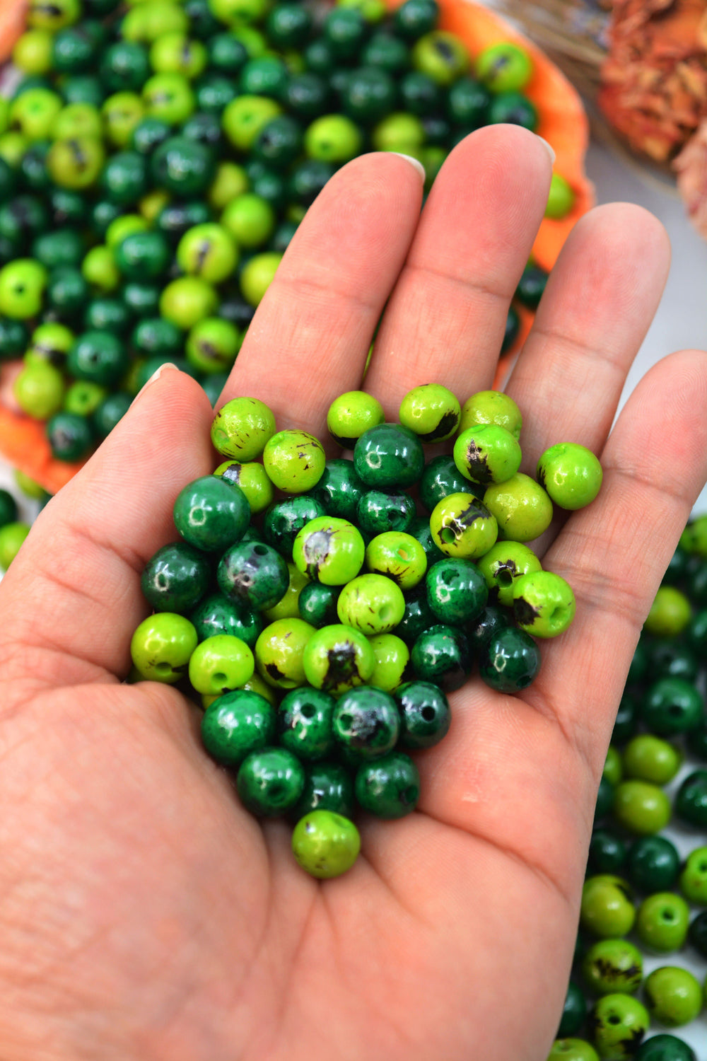 A close-up of Green Acai beads showing the natural black marking details.