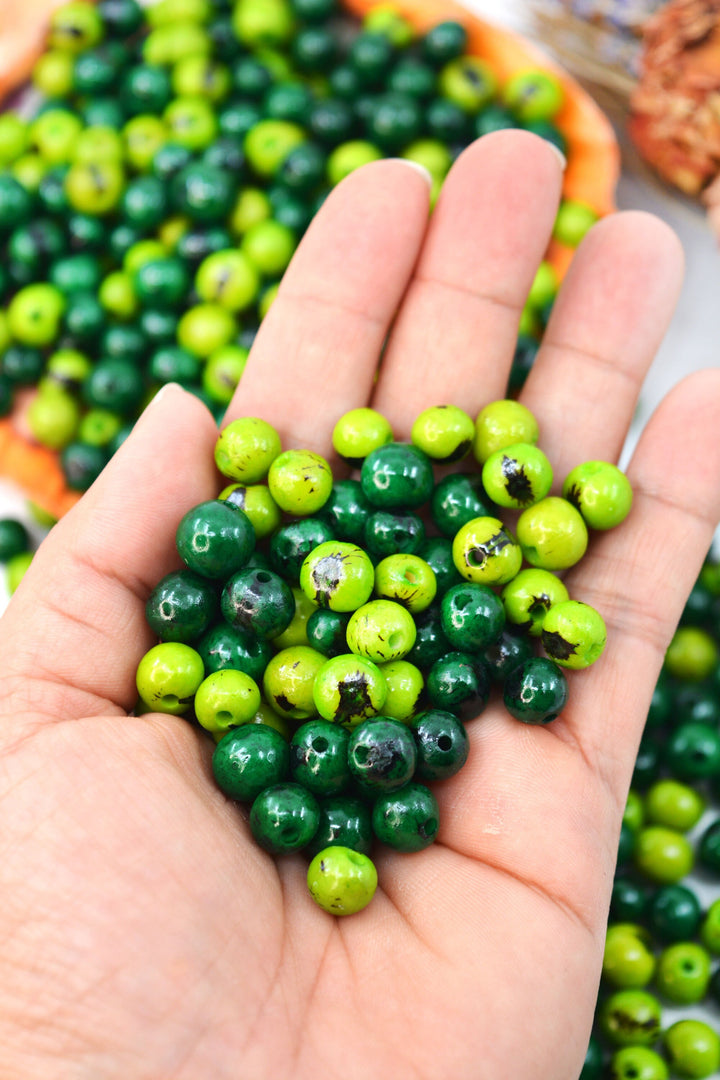 Green acai beads details in a jewelry makers hand.