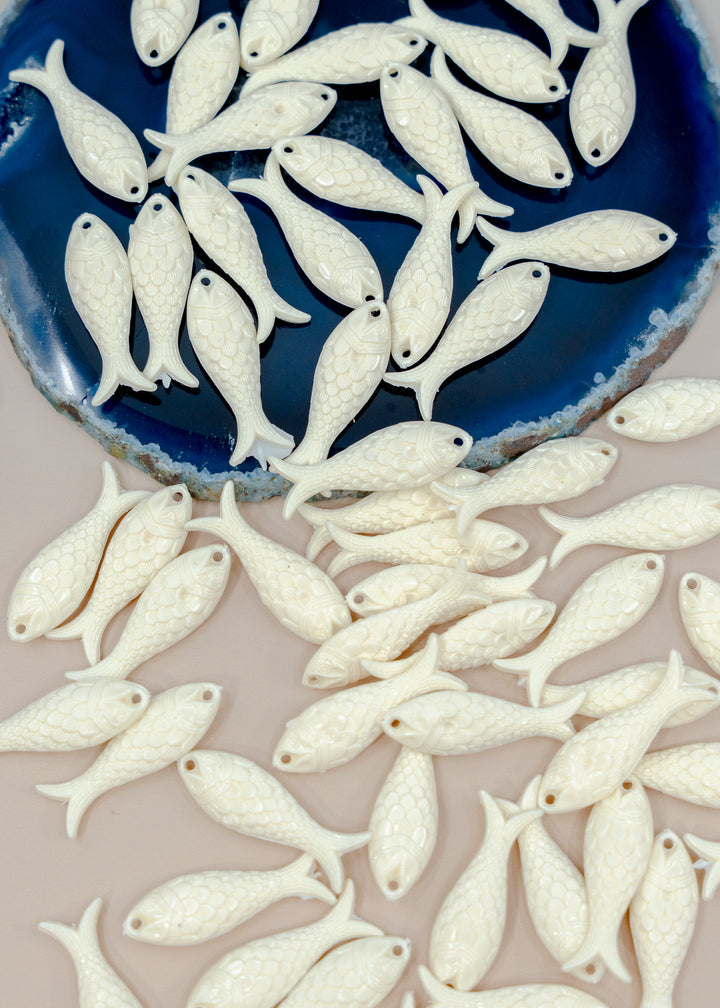 White fish-shaped charms for jewelry making.