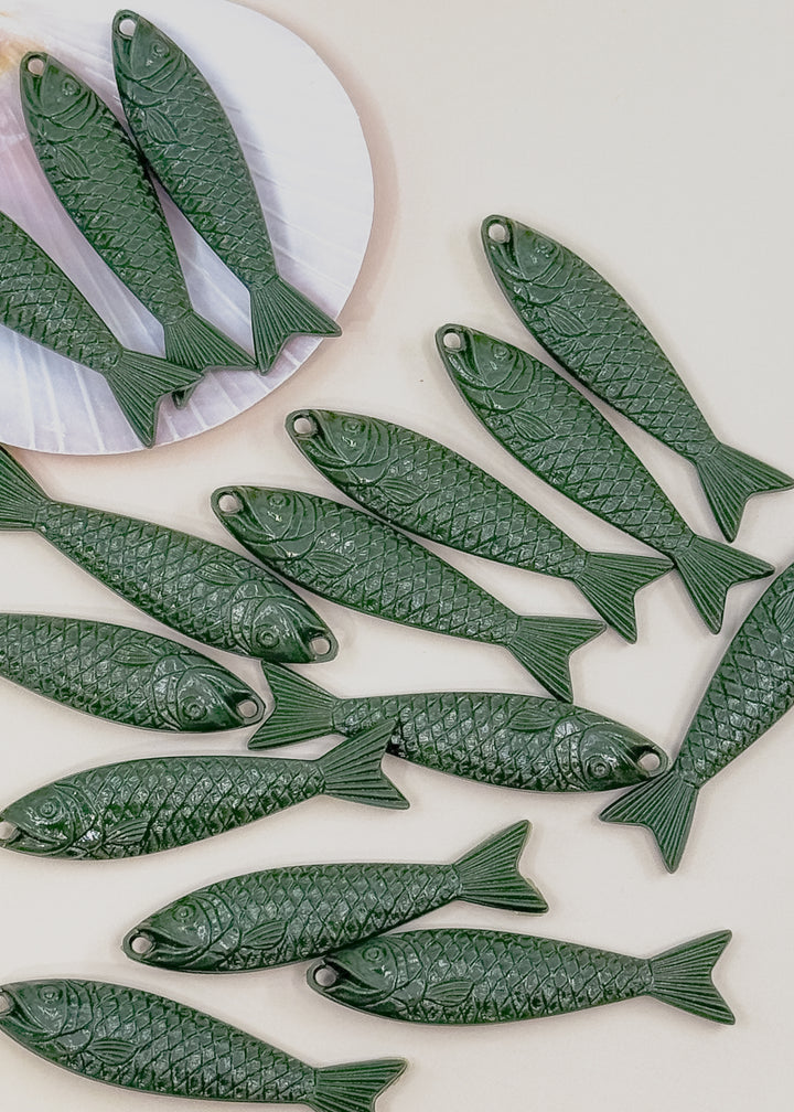 Multiple dark green fish-shaped jewelry charms with detailed scale engravings, sardine charms.