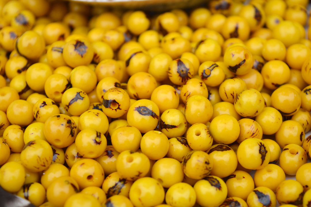 The detailed image of yellow acai beads showing the natural black marking of these natural beads.