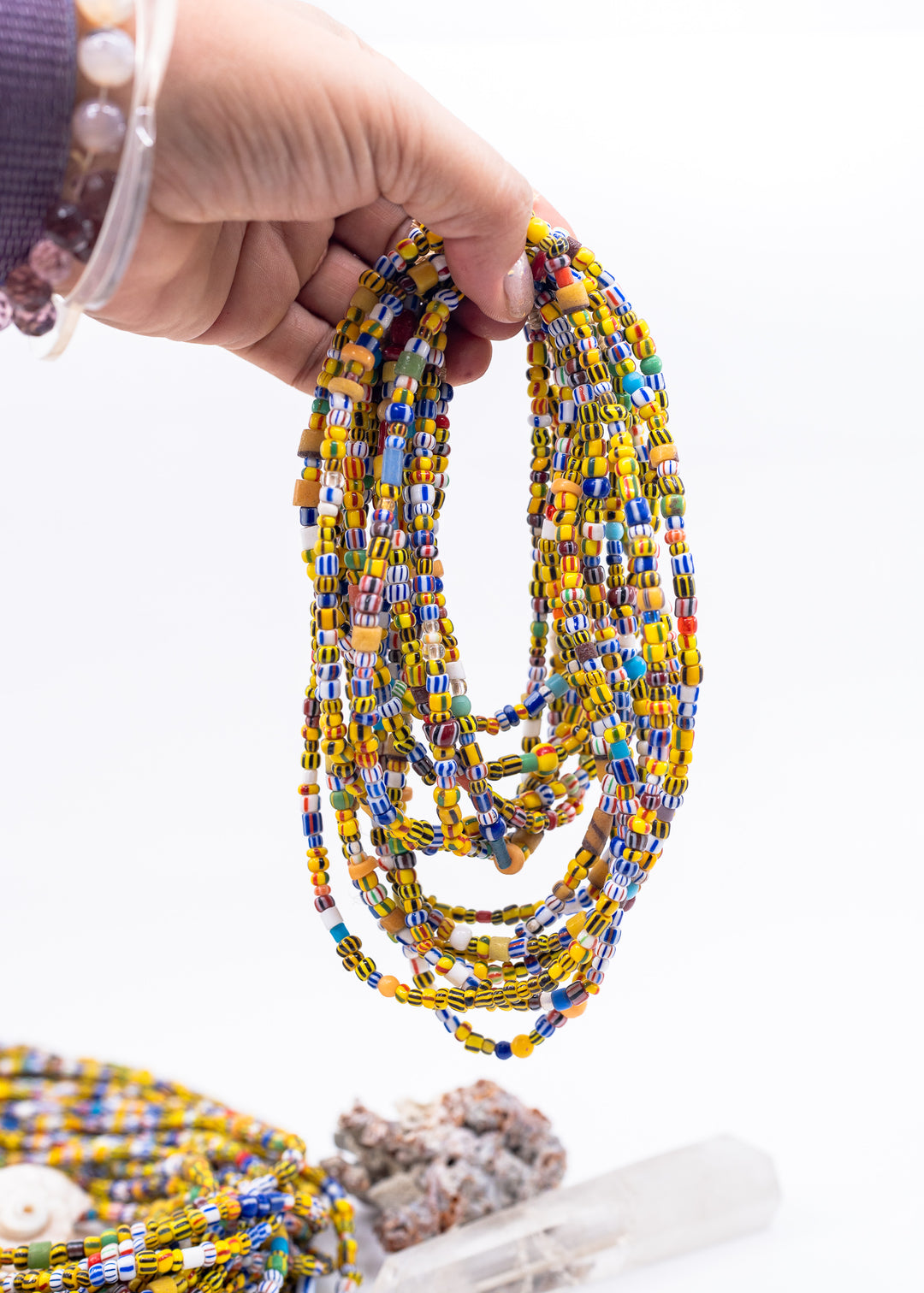 A hand hold several strands of African Ghana Beads
