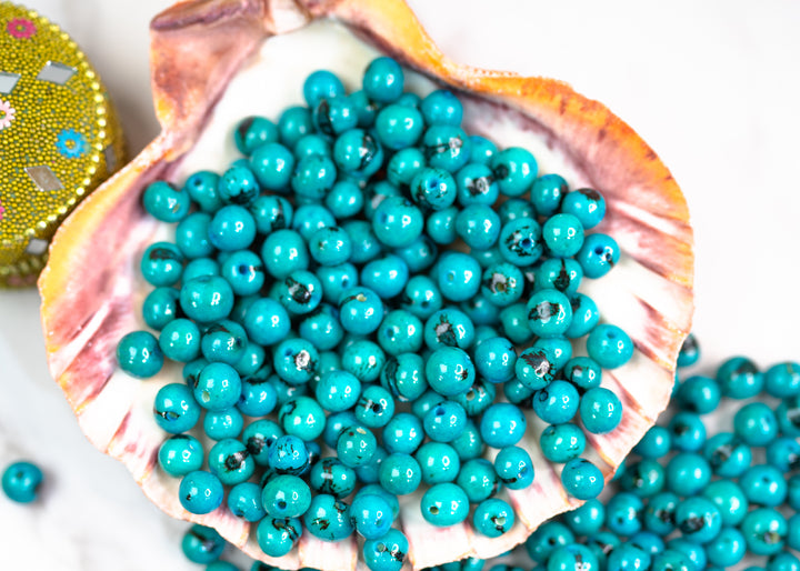 Details of Turquoise Blue Acai Beads showing the natural black marking.