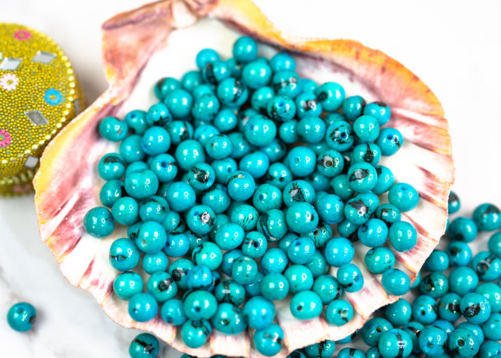 An assortment of Acai Beads in Turquoise Blue displaying the variance in size of these natural beads.