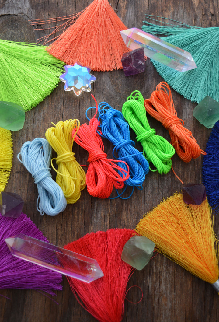 Colorful yarn strands and crystal prisms on a wooden surface
