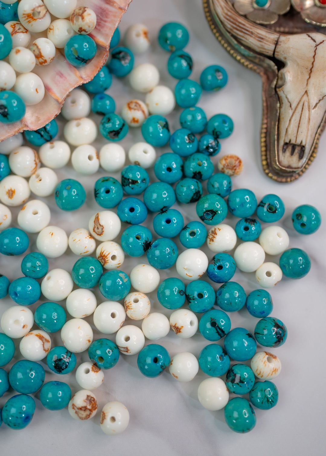 A collection of turquoise and white acai beads with a black line pattern.