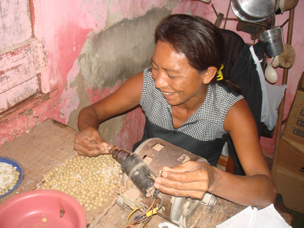 Local artisan drilling açaí seeds by hand in the Brazilian Amazon, photographed by Nature Beads founder Lilly