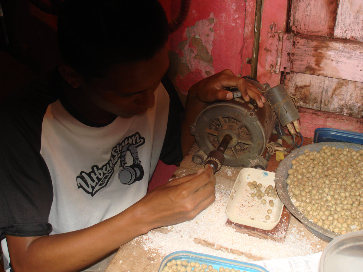Local artisan drilling açaí seeds by hand in the Brazilian Amazon, photographed by Nature Beads founder Lilly