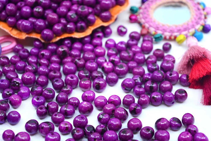 a display of purple acai beads showing the different sizes of natural beads