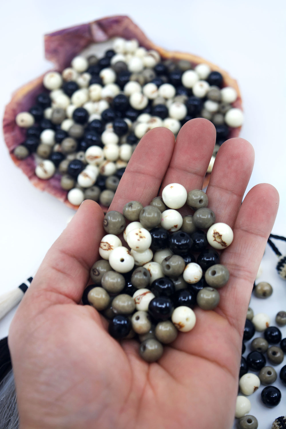 Black Pearl, Black, White and Gray Acai Beads close-up of the different sizes in the hand.