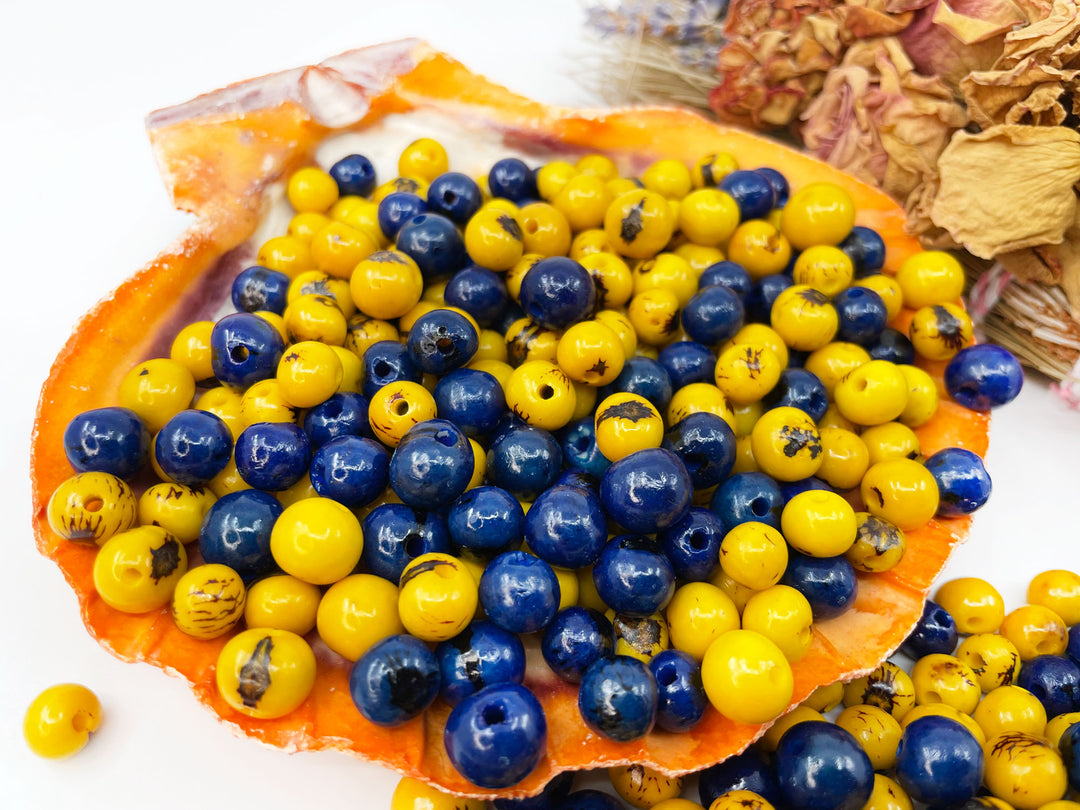 Beautiful display of blue and yellow acai beads displayed on a seashell.