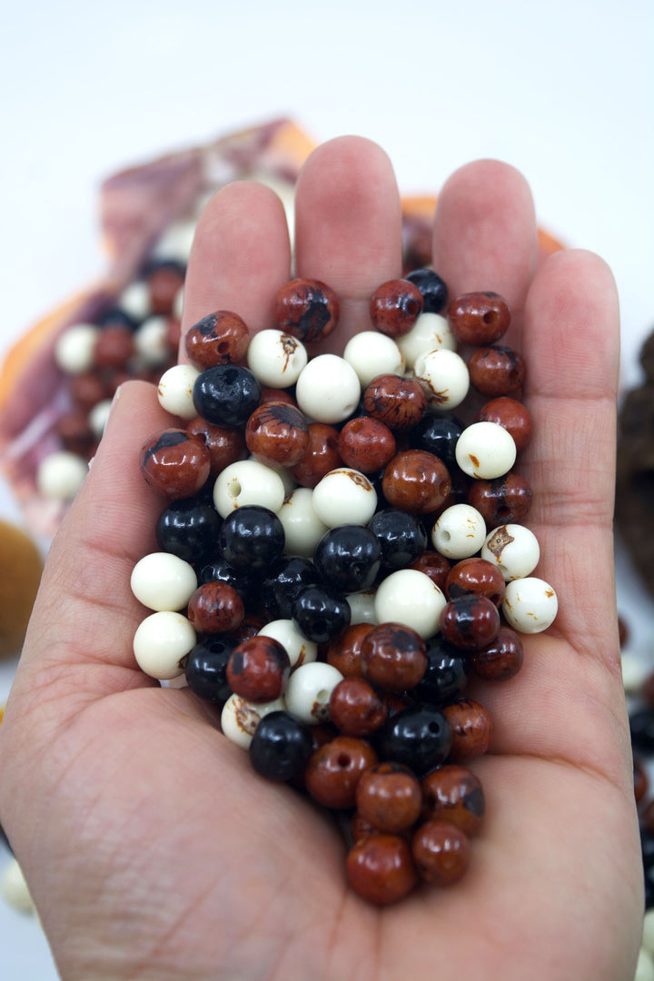 Cookies and Cream, Brown, White and Black Acai Beads close-up in the hands.