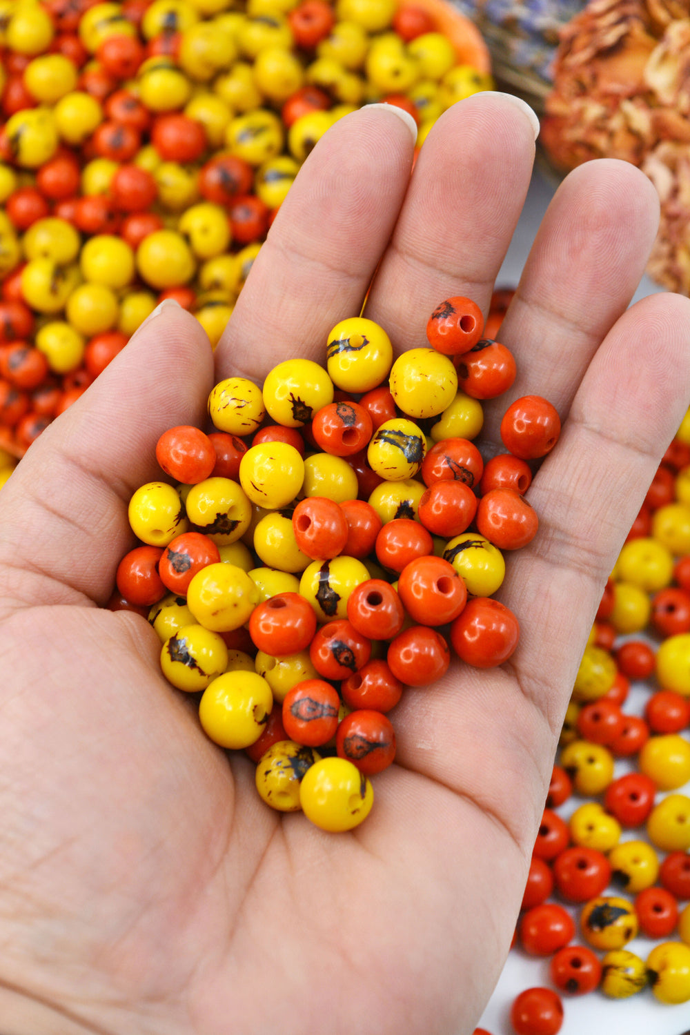 A close-up of yellow and orange acai beads in the hands.