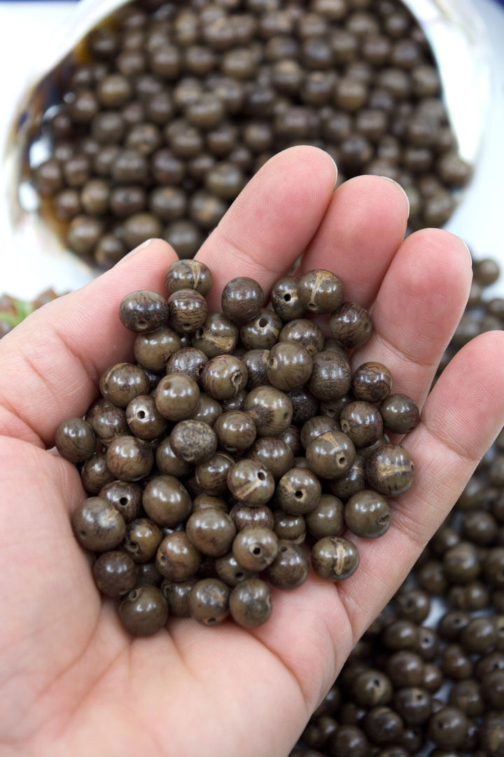 Clay Brown Acai Beads close-up in the hands.