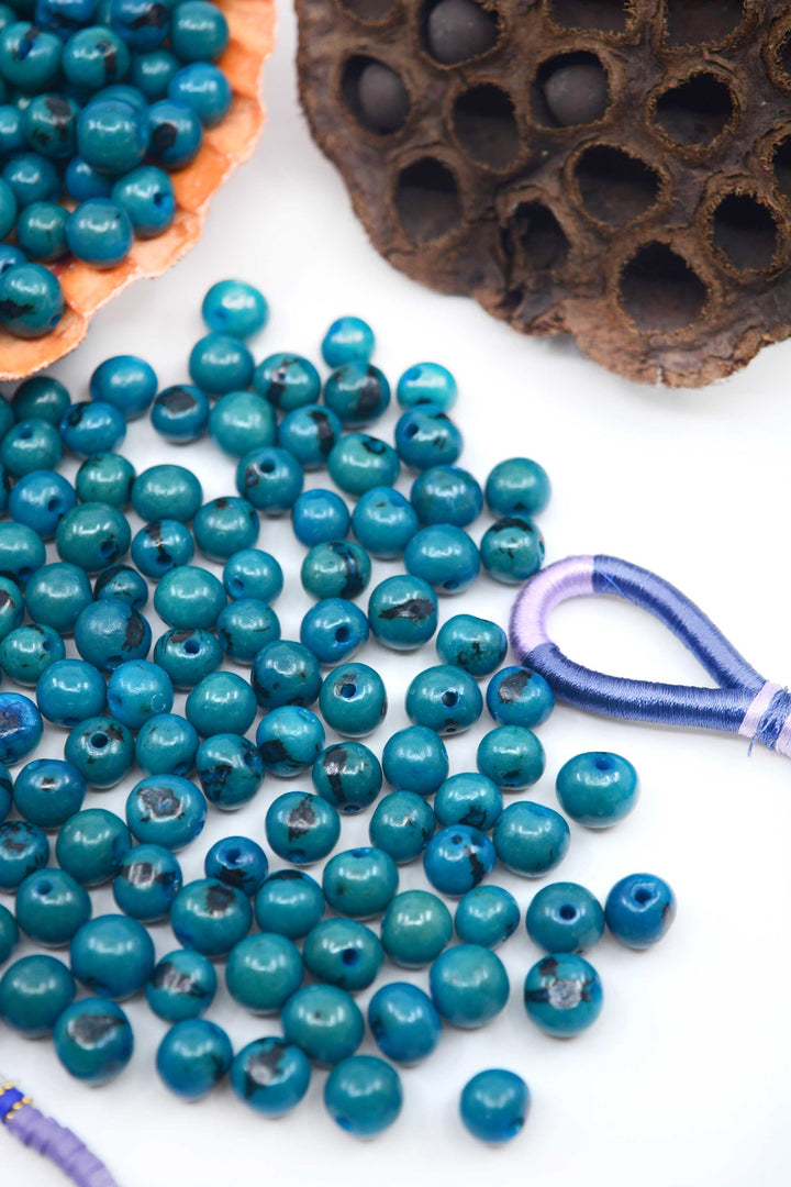 Deep Turquoise Blue Acai Beads showing the size of the holes in the beads for jewelry making.