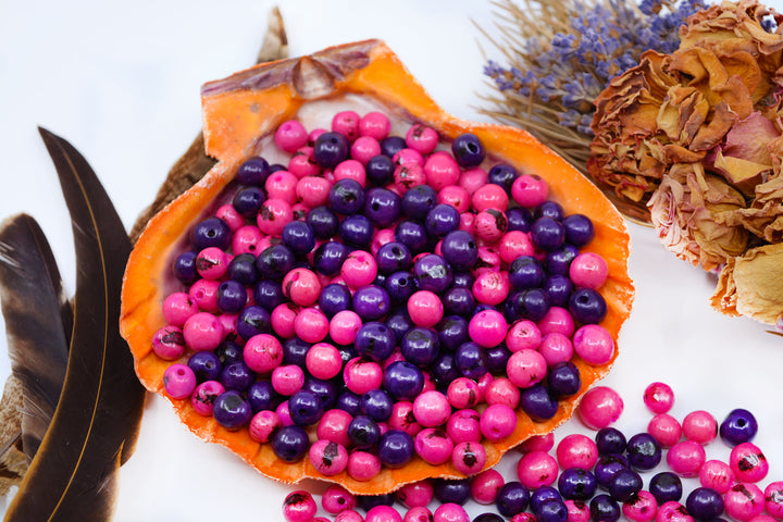 Natural Pink and Purple Acai Beads displayed in a seashell for jewelry making.