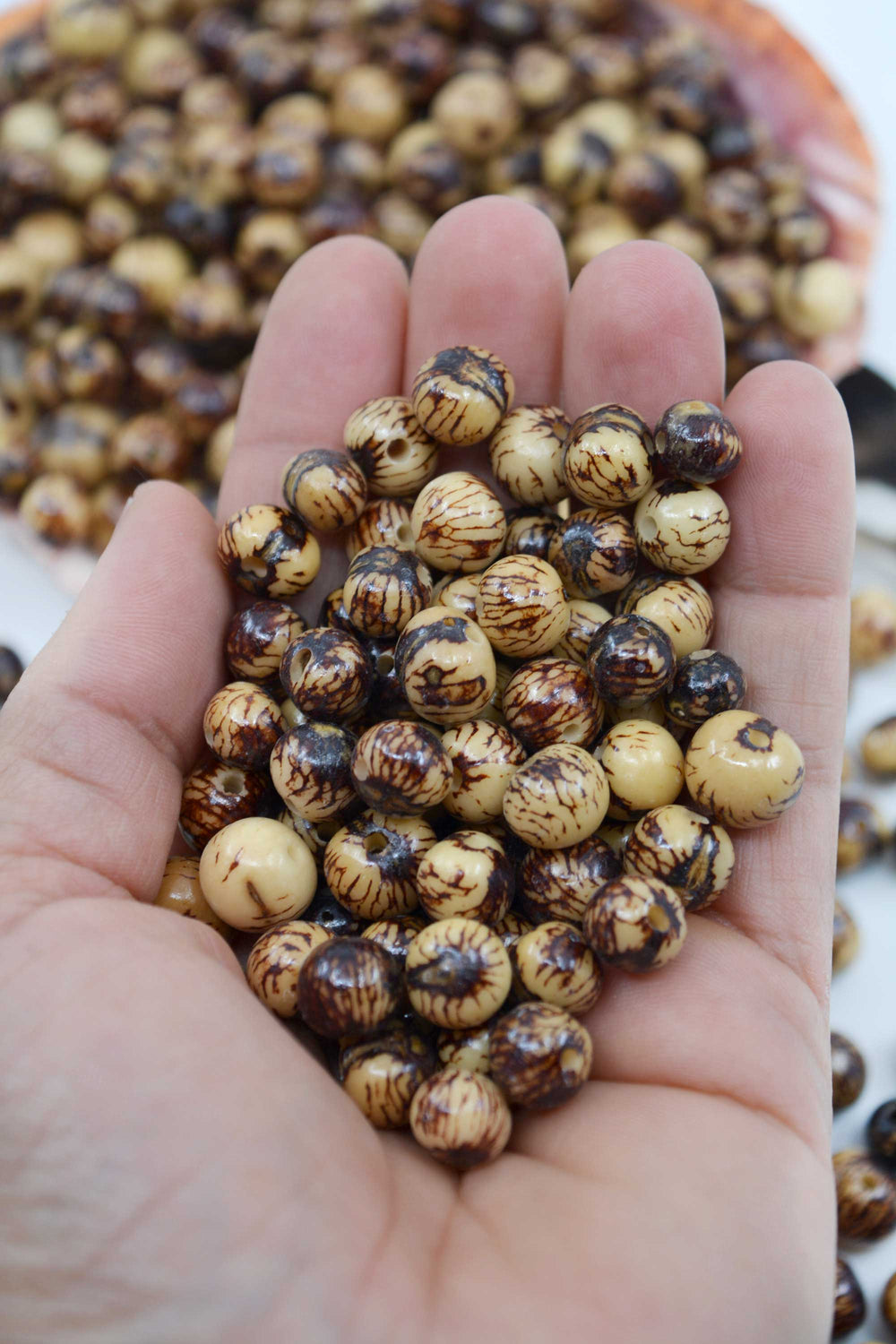 Natural Brown and Cream Real Acai Beads close-up in the hands.