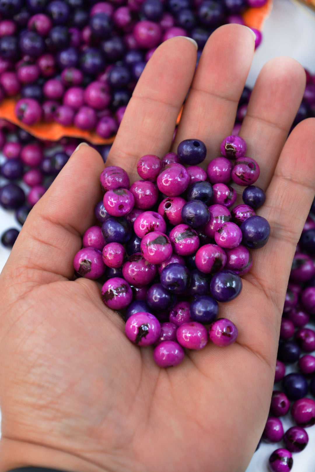 Close-up of purple acai beads in the hands.