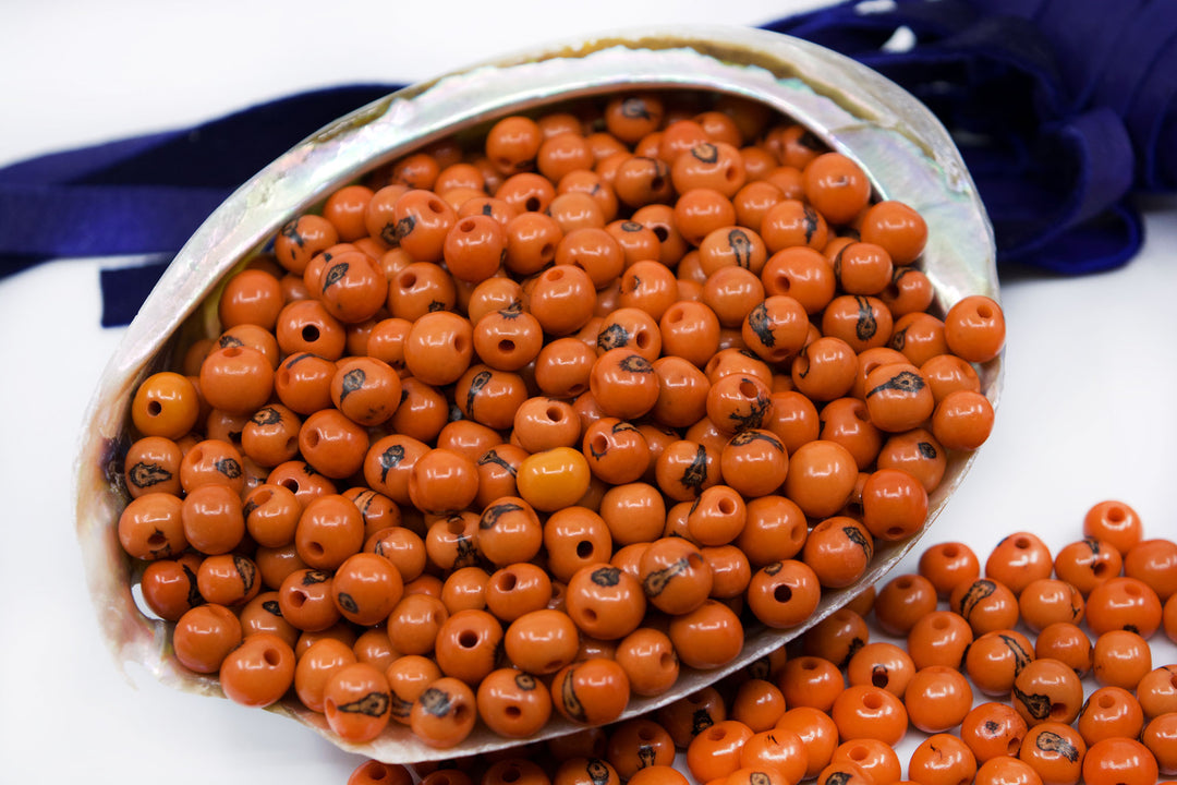 A bunch of acai beads showing the variance in size displayed in an abalone seashell.