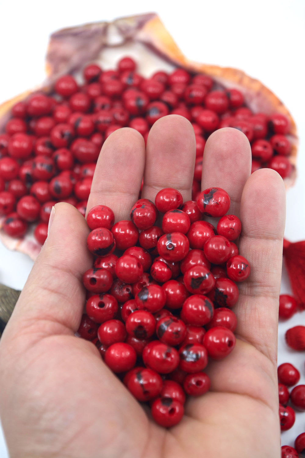 Scarlet Red Acai Beads close-up in the hands for jewelry making.