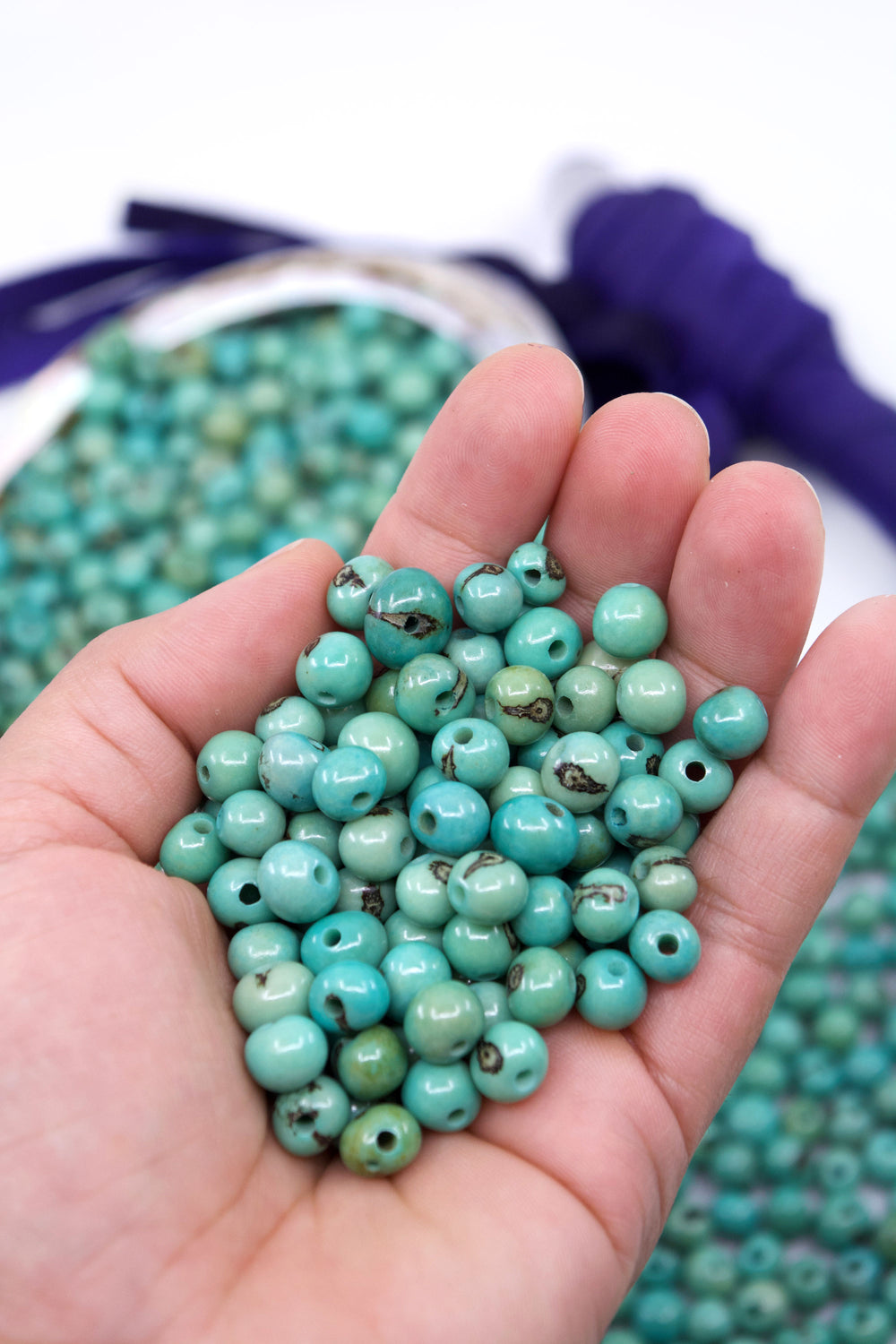 A close-up of Seafoam Blue acai beads showing the difference in size.