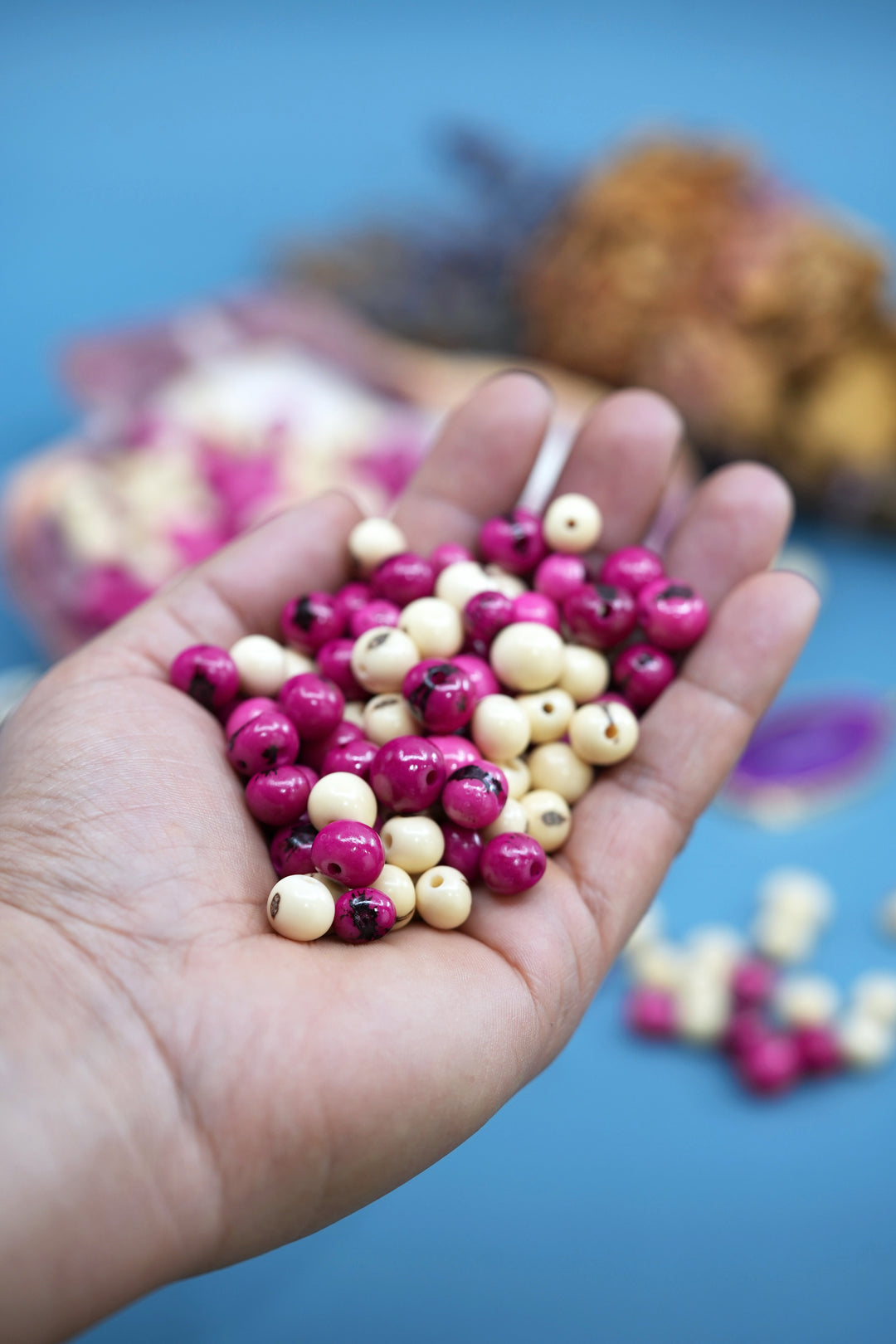 Close-up of Pink and White Acai Beads in the hands displaying the bead size.