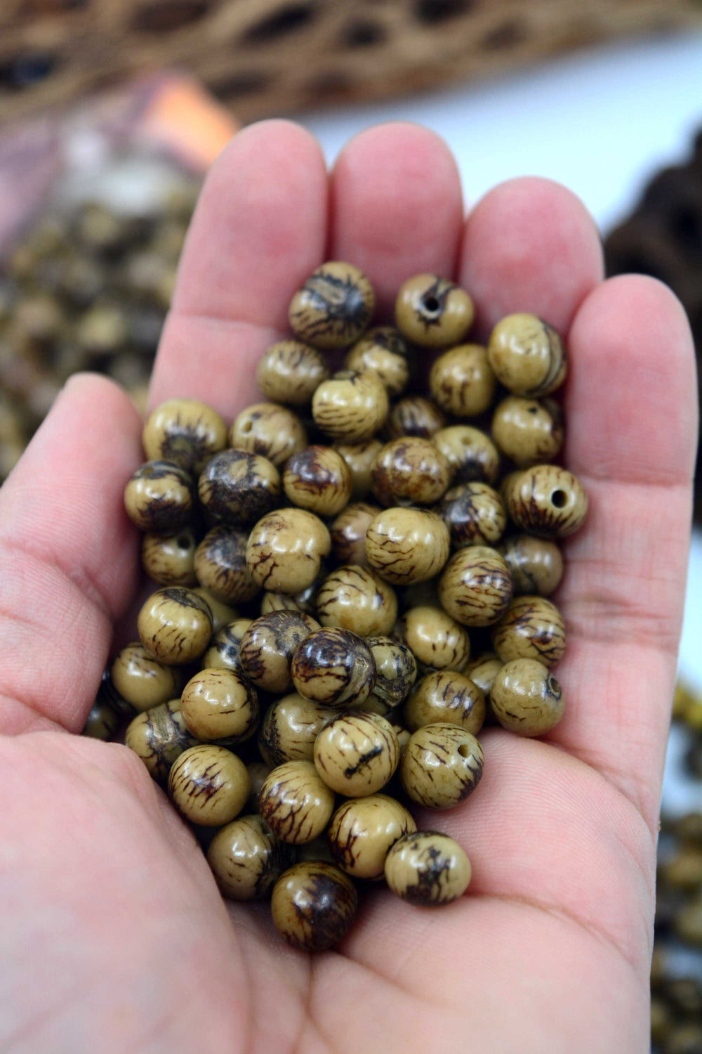 Close-up of Green Tiger acai beads in the hands.