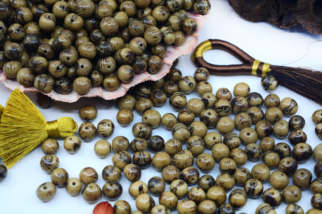 Acai Beads in an Olive Green shade showing the natural black markings.