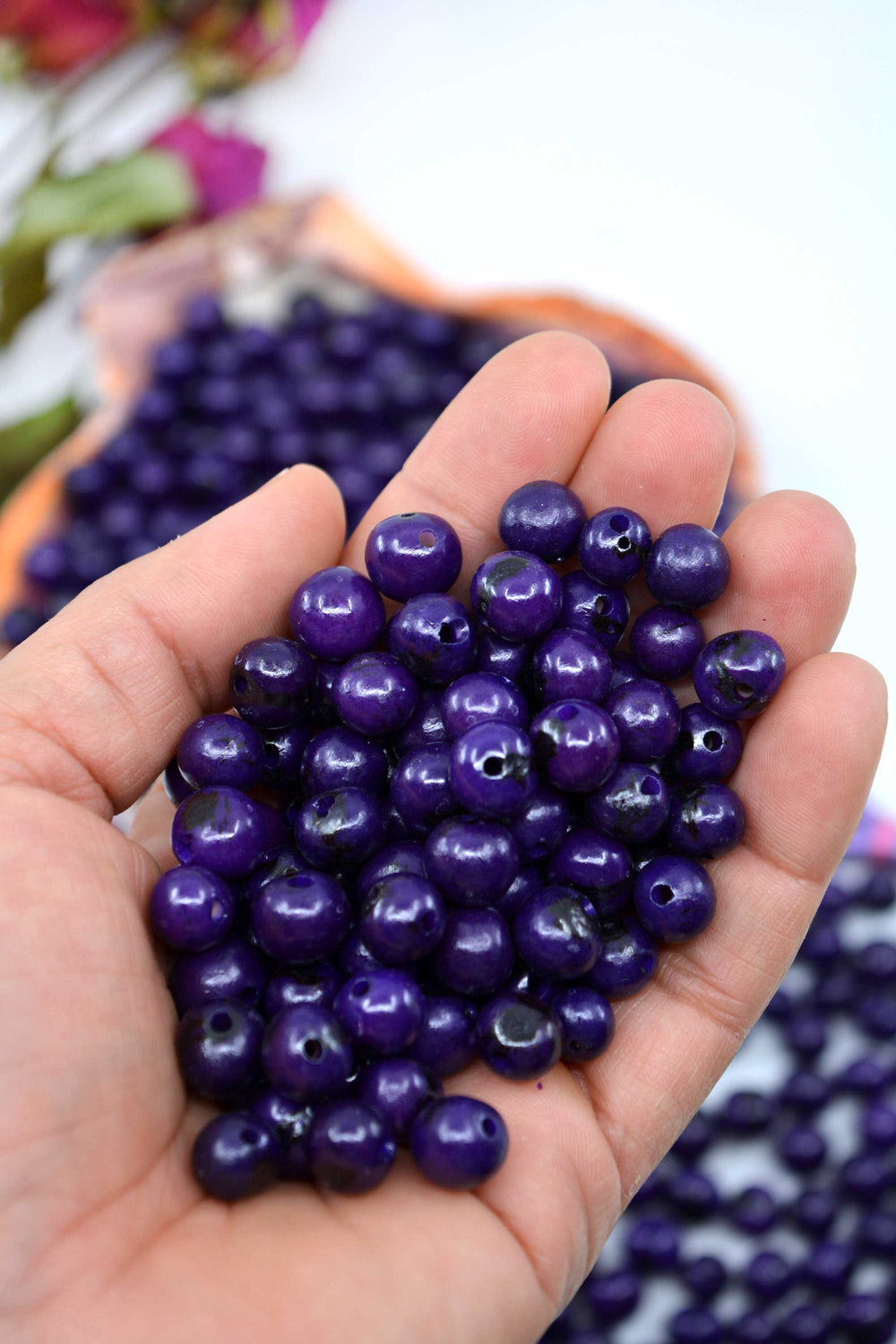 Violet Purple Acai Beads close-up in the hand.