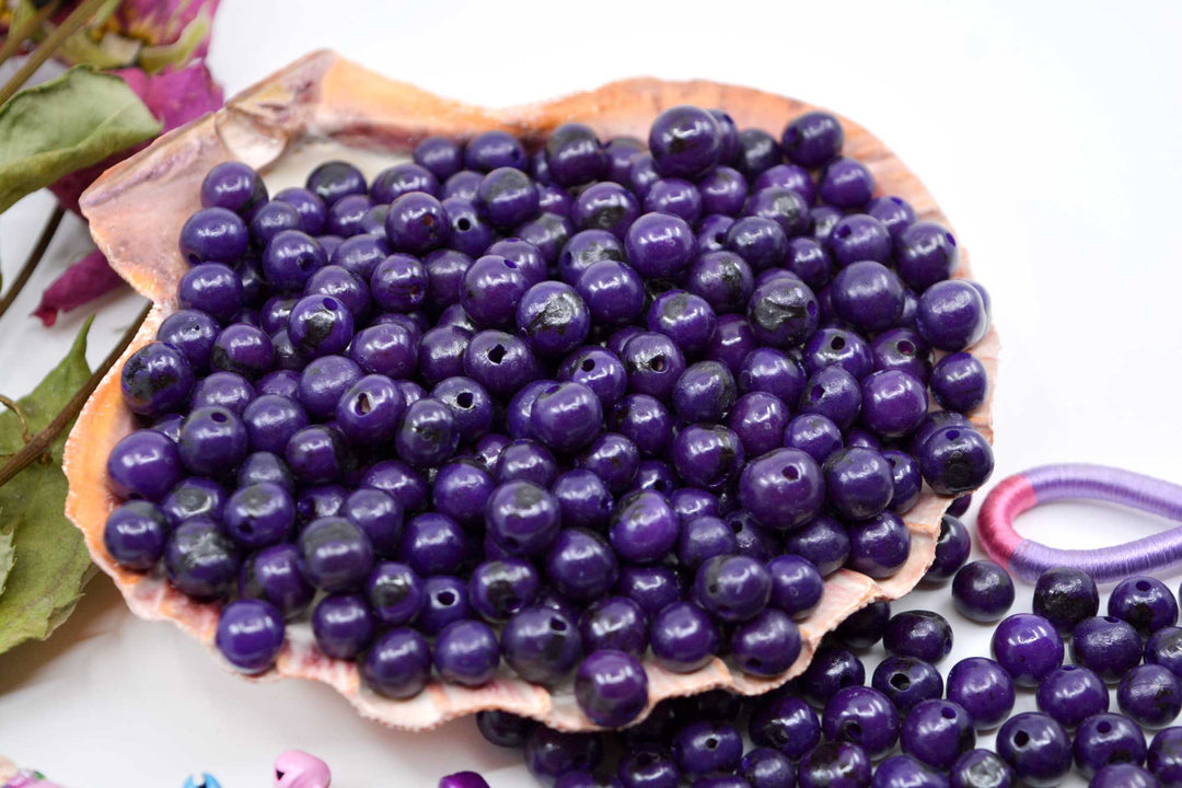 Violet Purple Acai Beads displaying the variance of the beads and showing the holes of the beads.