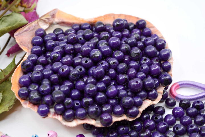 Violet Purple Acai Beads displaying the variance of the beads and showing the holes of the beads.